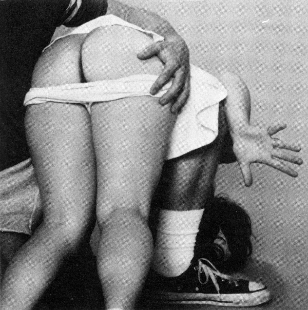 Een tennisspeelster ligt bij de tennisleraar over de knie en krijgt op haar blote billen.