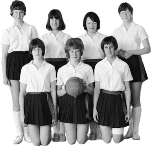 Zeven jonge vrouwen in bijpassende uniformen poseren voor een zwart-wit teamfoto; één op de eerste rij houdt een bal vast.